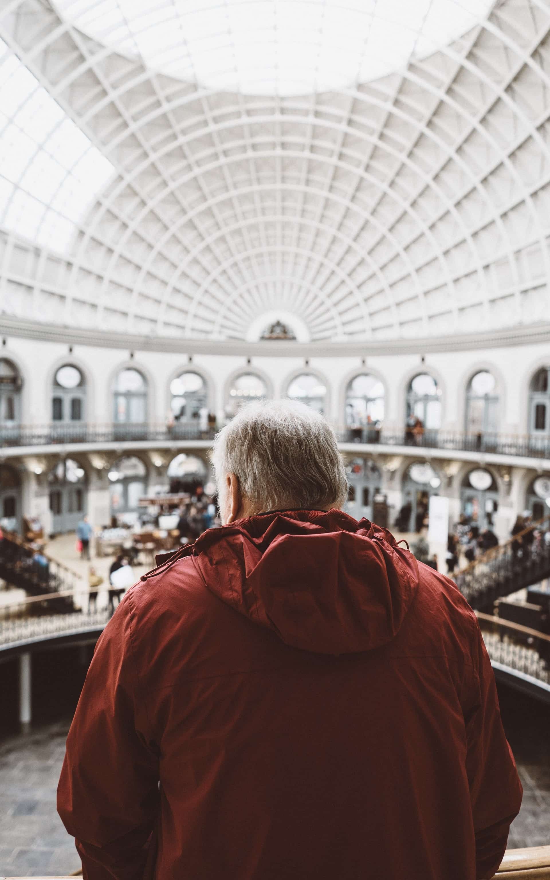 man in red jacket looking over a big room.