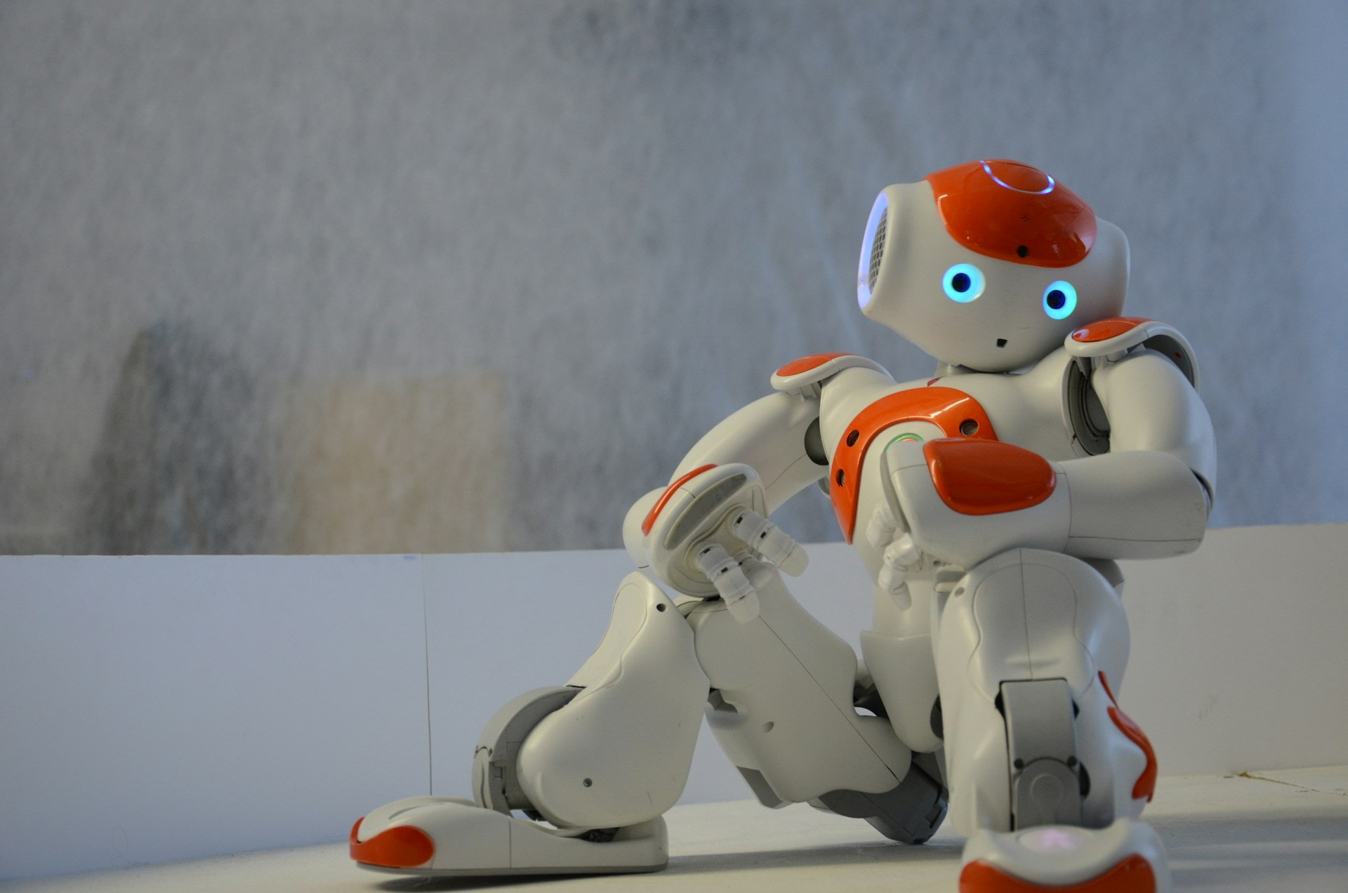 White robot sitting with orange details and blue eyes